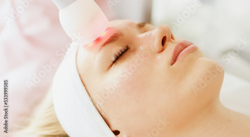 Beautician cosmetologist doing facial skin procedure with electroporation device in a beauty clinic salon for client. Skincare and machine cosmetology spa concept. 