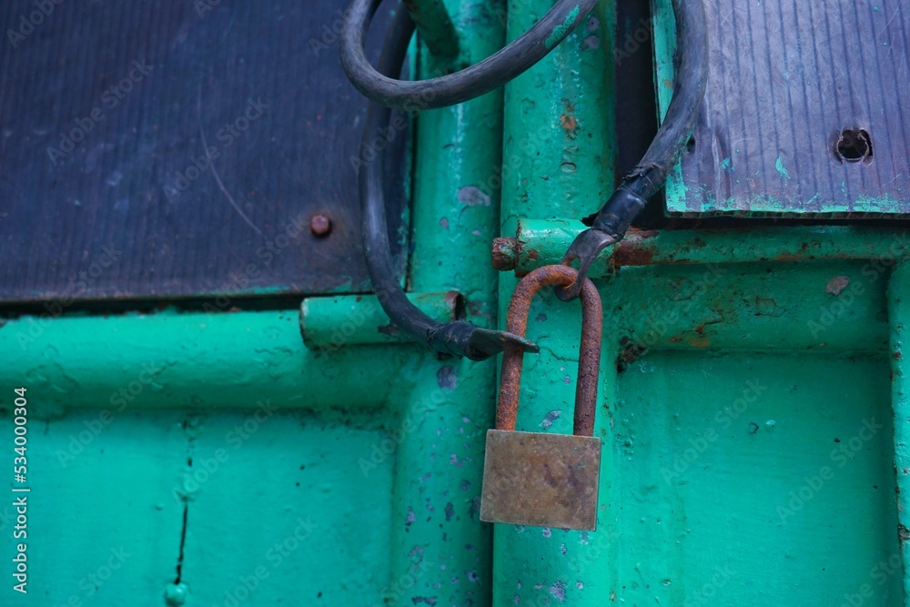 green painted metal door locked with rusty padlock green painted metal door locked with rusty padlock
