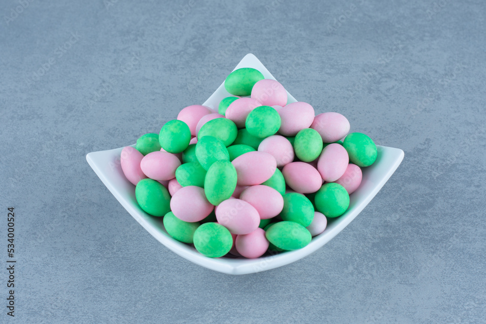 Small colorful chocolate in the bowl, on the marble background Small colorful chocolate in the bowl, on the marble background