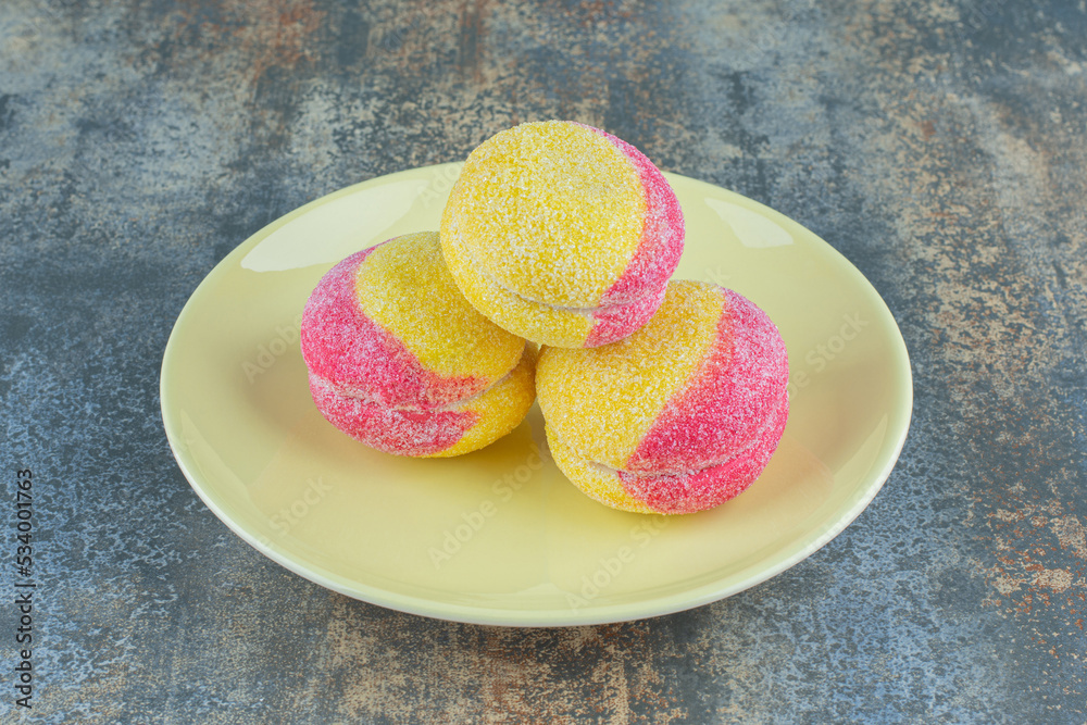 A pile of peach shaped cookies on the plate, on the marble background A pile of peach shaped cookies on the plate, on the marble background