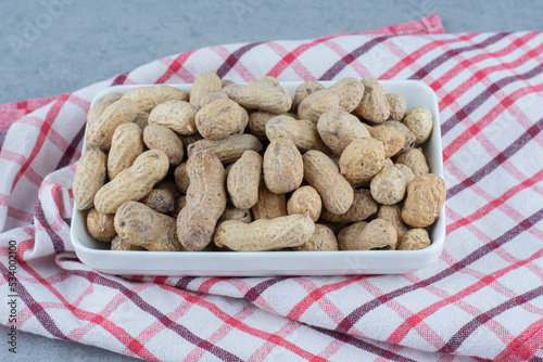 shelled peanuts in the bowl, on the towel, on the marble background photo