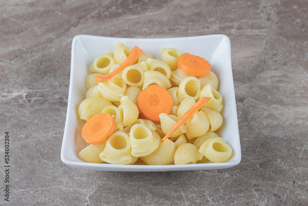 Delicious pasta with sliced carrot in bowl , on the marble background Delicious pasta with sliced carrot in bowl , on the marble background