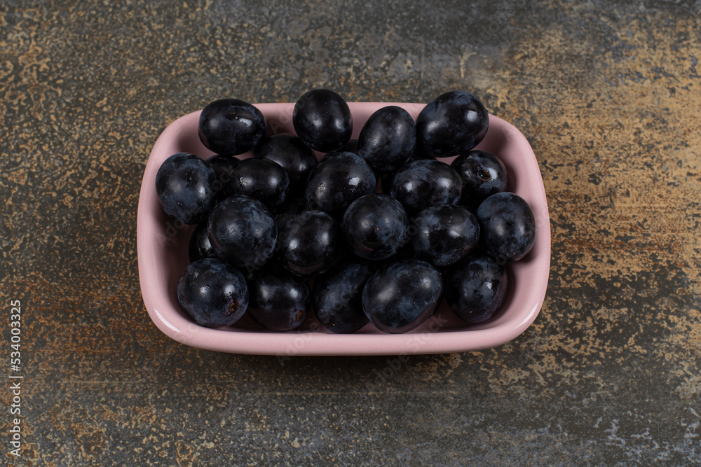 Bunch of black grapes in pink bowl Bunch of black grapes in pink bowl