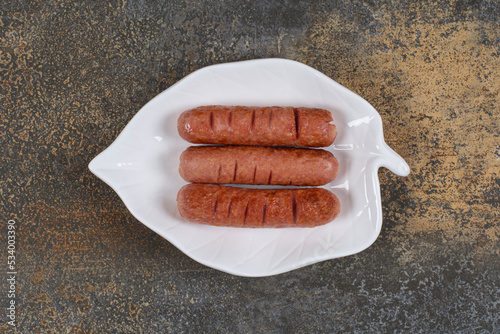 Roasted tasty sausages on leaf shaped plate photo