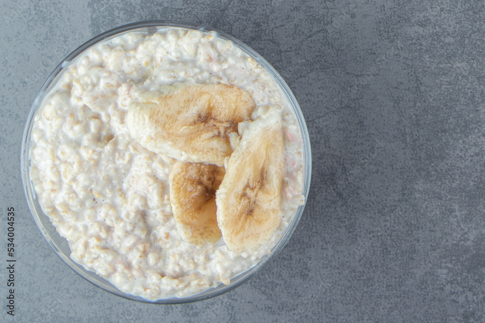 A glass plate of oatmeal porridge with slices of banana A glass plate of oatmeal porridge with slices of banana