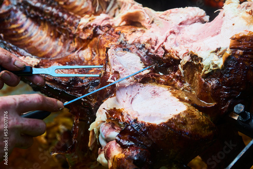 Chef Hands cutting whole grilled pork for steaks with knife. Pig grilled traditional coal and fire. The little piglet is roasted whole on an open fire. Pig on the spit