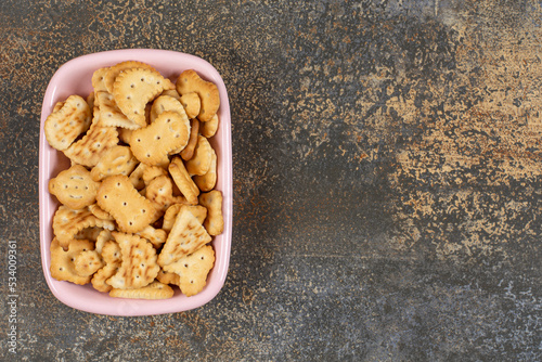 Pile of salted crackers in pink bowl
