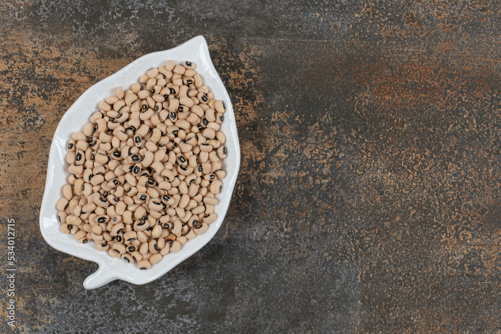 Pile of dry white beans on leaf shaped plate Pile of dry white beans on leaf shaped plate