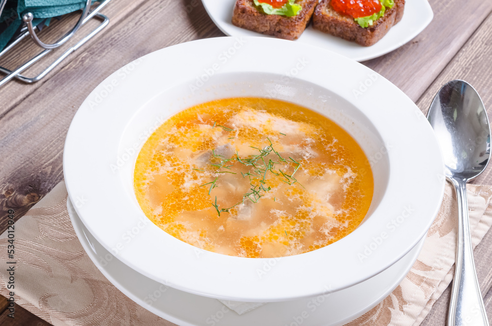 Fish soup - tsarist Russian fish soup with sandwiches with red caviar in a plate on a dark wooden background Fish soup - tsarist Russian fish soup with sandwiches with red caviar in a plate on a dark wooden background