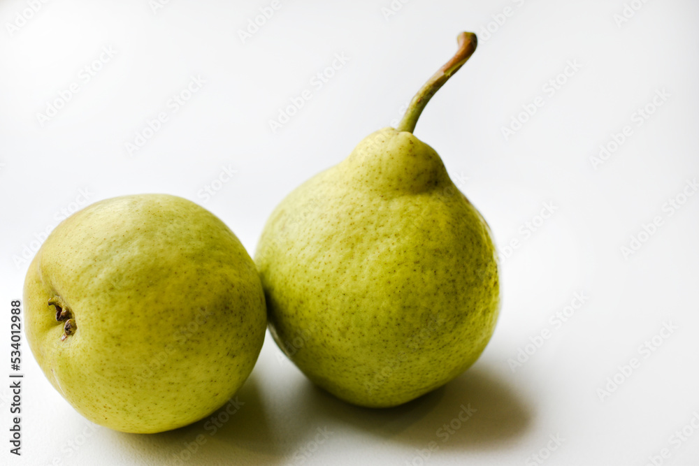 Two green ripe pears on a white background in autumn. Two fruits of a green pear in close-up. Two green ripe pears on a white background in autumn. Two fruits of a green pear in close-up.