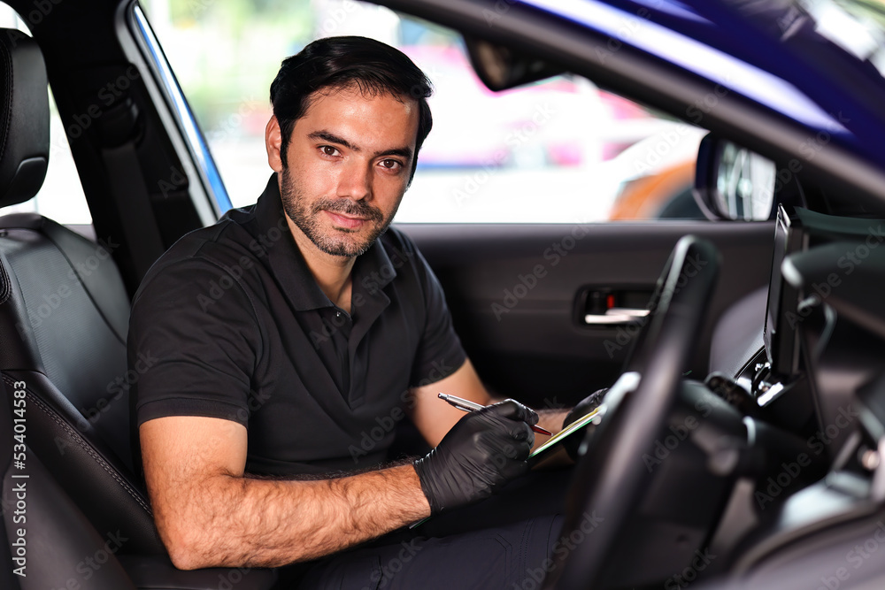 Portrait of an Auto Service Technician holds a pre-delivery inspection checklist for physical and interior inspection that the car repair shop. Portrait of an Auto Service Technician holds a pre-delivery inspection checklist for physical and interior inspection that the car repair shop.