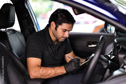 Portrait of an Auto Service Technician holds a pre-delivery inspection checklist for physical and interior inspection that the car repair shop.