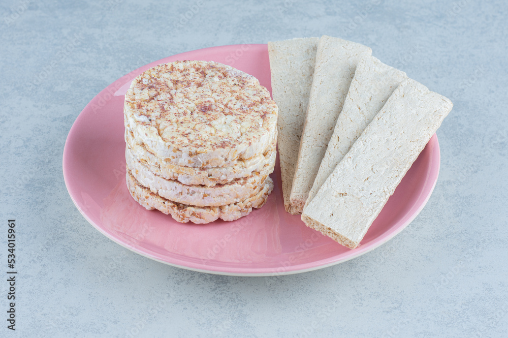 Puffed rice cakes and sweet cracker in the plate, on the marble background Puffed rice cakes and sweet cracker in the plate, on the marble background