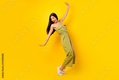 Full size photo of adorable cheerful vietnamese girl stand tiptoe dance good mood isolated on yellow color background photo