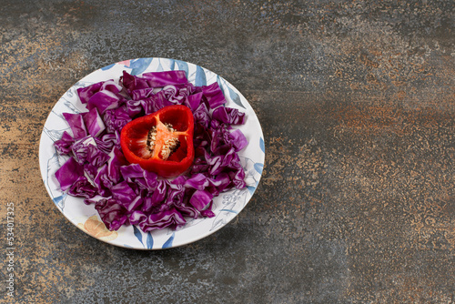 Chopped cabbage and pepper in a plate, on the marble background