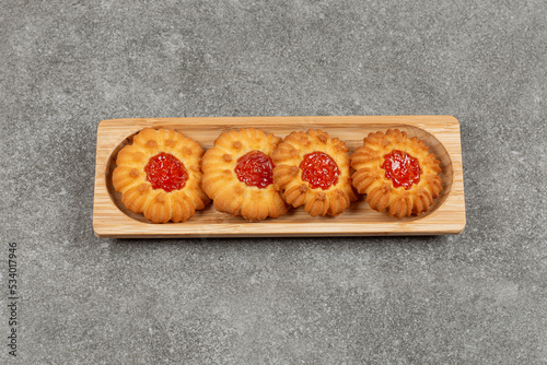Flower shaped biscuits with jelly on wooden board