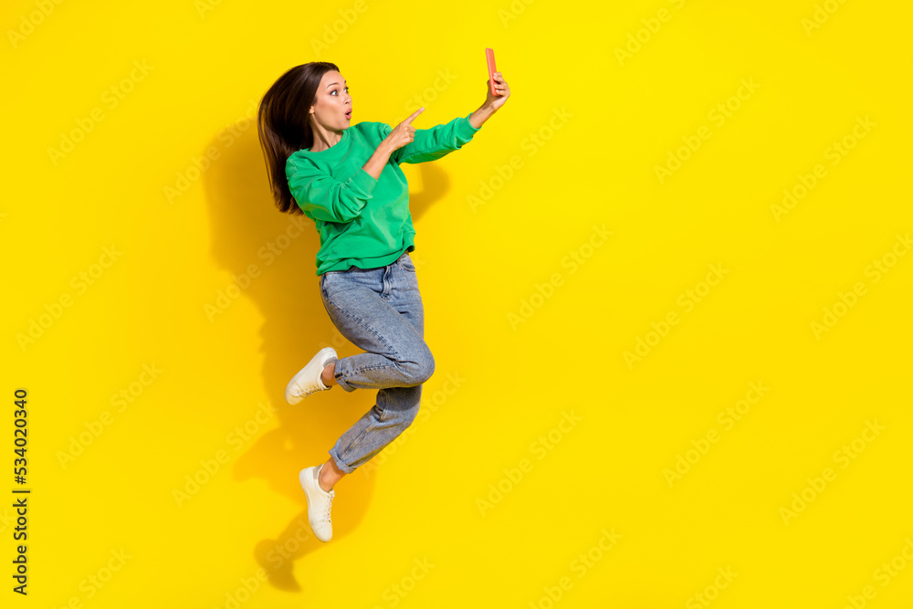 Full length portrait of impressed person jump point finger telephone isolated on yellow color background Full length portrait of impressed person jump point finger telephone isolated on yellow color background