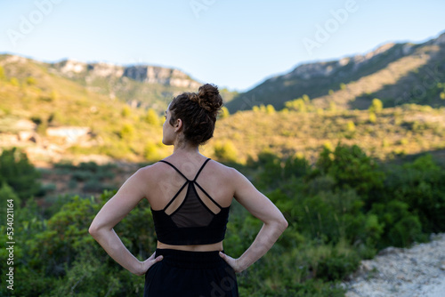 Caucasian woman from behind staring at the mountain with black top