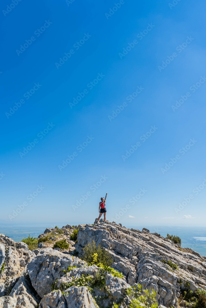 Victorious happy woman with arms in the air on top of a mountain