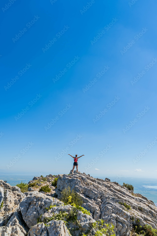 Fototapeta premium Victorious happy woman with arms in the air on top of a mountain