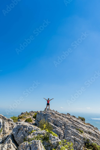 Victorious happy woman with arms in the air on top of a mountain