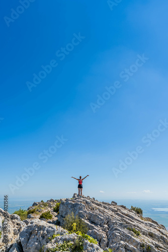 Victorious happy woman with arms in the air on top of a mountain