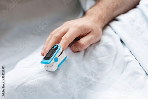 Male hands with a pulse oximeter on the index finger, close-up. A hospitalized patient is in the hospital. Concept of determination of oxygen in the blood photo