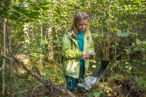 A woman with her mobile phone in the forest. Playing geocaching. photo