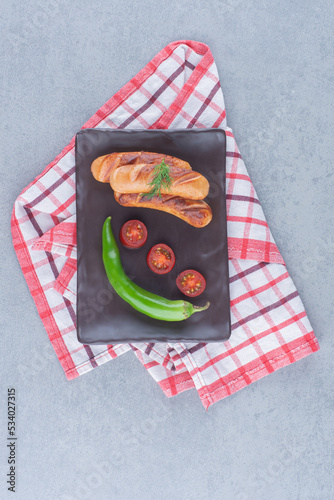 Fried Sausages with vegetables on black board
