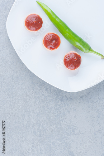 Green hot chili pepper with ketchup on white plate photo