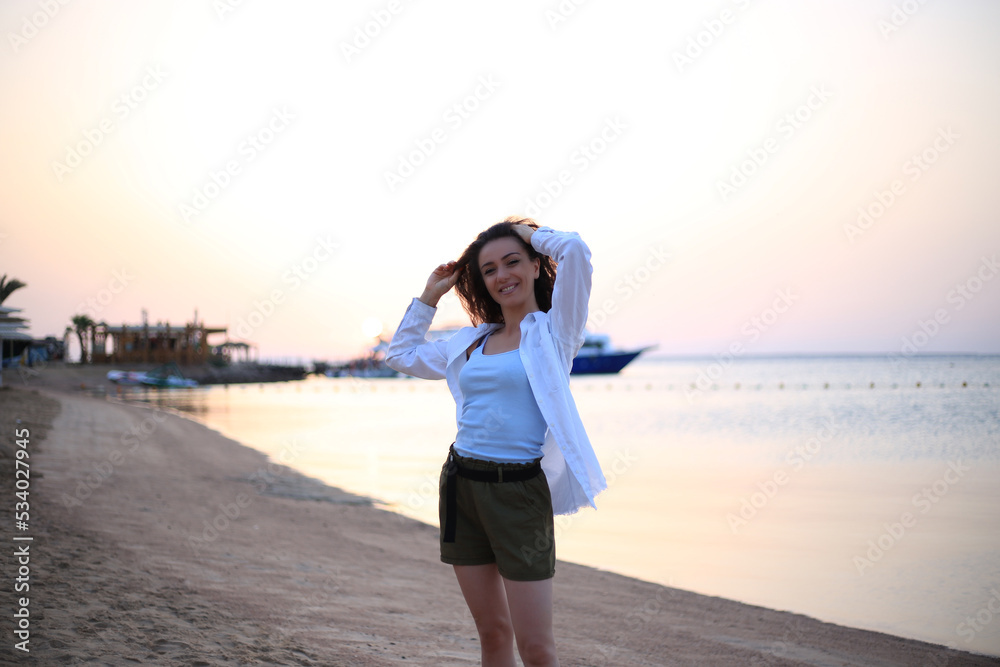 Stylish young woman posing near lake on summer day sunset
