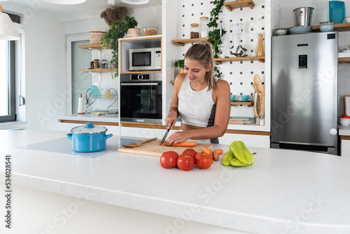 Young woman cancer survivor cooking and preparing vegetarian meal after long heavy sickness. Vegan female in the kitchen making healthy lunch from fresh vegetables changing way of life after illness.