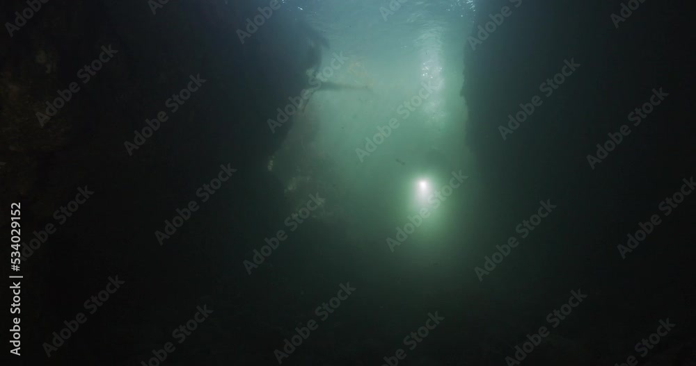 Scuba diver swimming into underwater cave. Scuba diver swimming into underwater cave.
