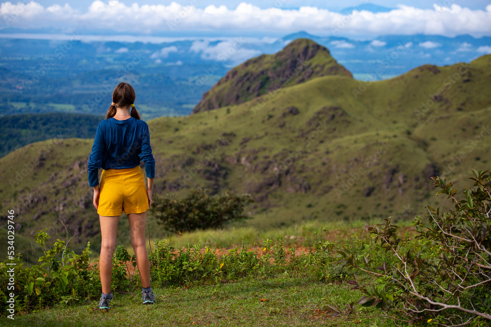 Naklejka premium woman in hiking boots watching the view from the top of the mountain in costa rica, cerro pelado; brave hiker girl enjoying the view from the top after a hard hike