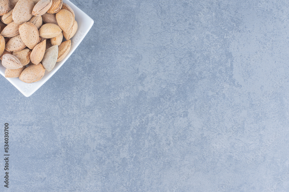 A bowl of tasty almonds, on the marble background A bowl of tasty almonds, on the marble background
