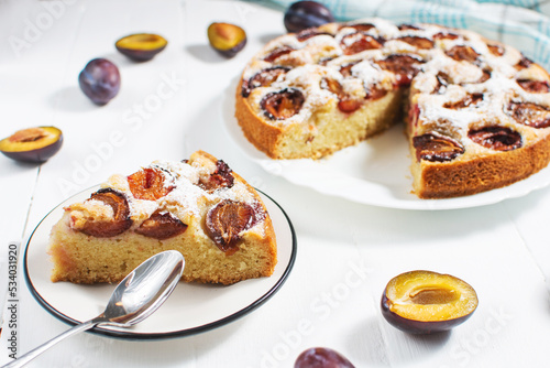 Homemade delicious plum tart with with sugar powder on white wooden table