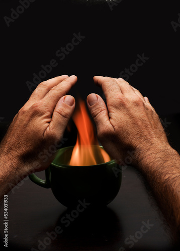 man's hands over cup with fire to warm up. energy poverty. 122 / 5.000 Resultados de traducción gas cuts, energy poverty, energy crisis, shortages, power outages, restrictions. time lock.