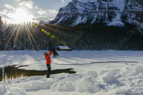 Father lifting his son up in the air at Lake Louise on a sunny winter morning