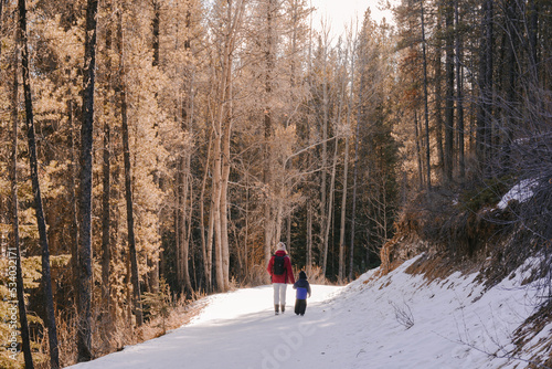 Woman and child walking on a snowy forest