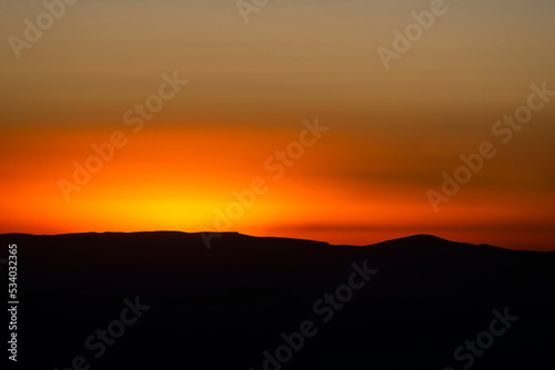 Panoramic view form mountains peak on the bright sunset with clouds.