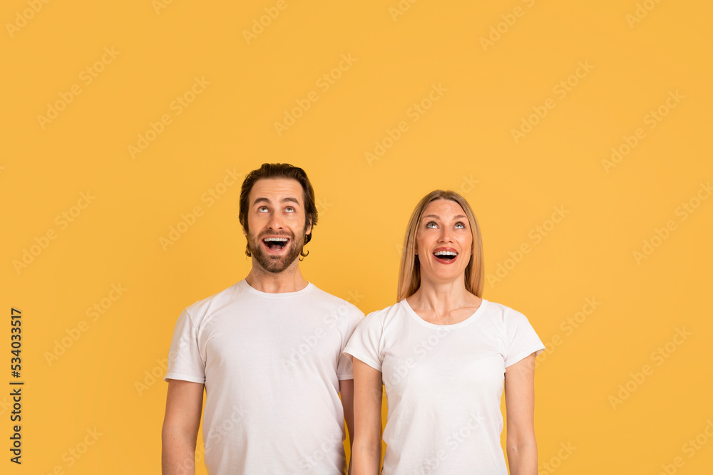 Emotions of great ad and offer. Shocked happy young caucasian woman and man in white t-shirts with open mouths