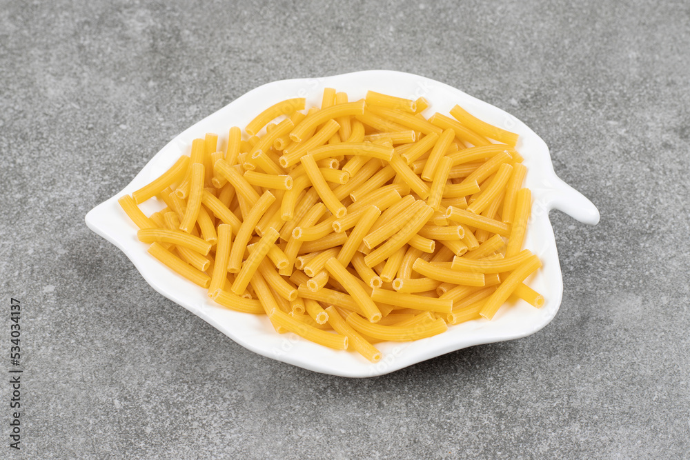 Heap of raw macaroni on white plate Heap of raw macaroni on white plate