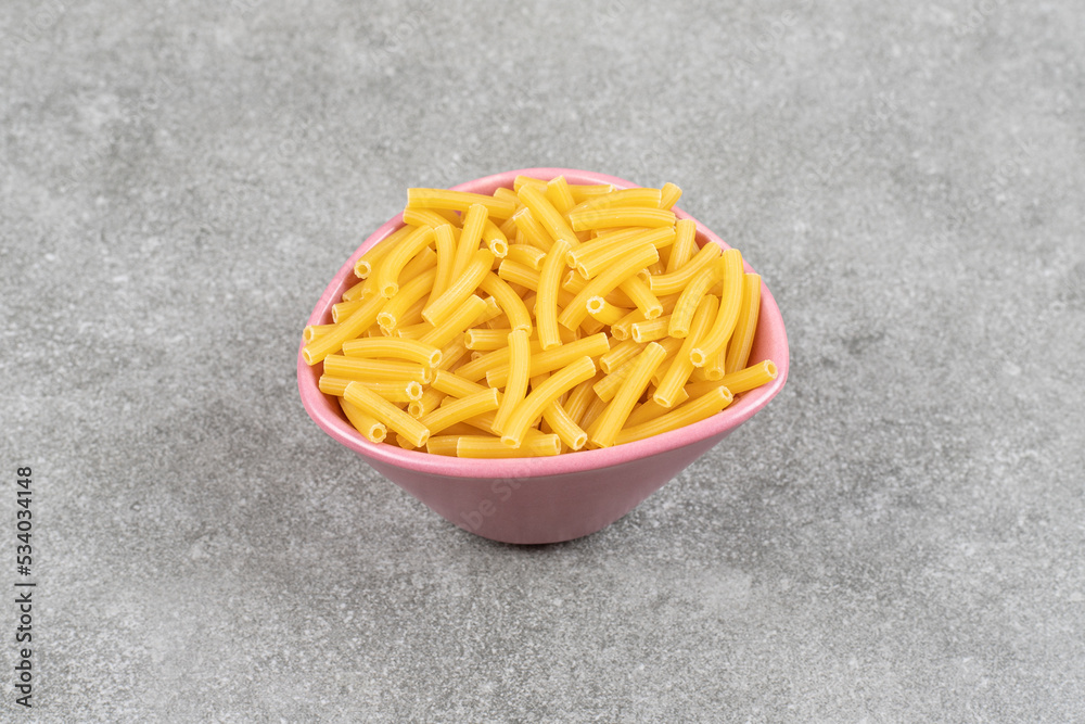 Heap of raw macaroni in pink bowl Heap of raw macaroni in pink bowl