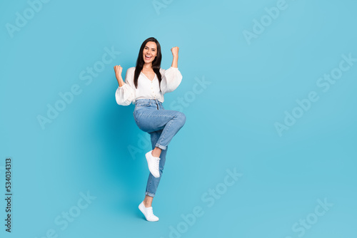 Full body portrait of overjoyed cheerful lady raise fists accomplishment empty space isolated on blue color background