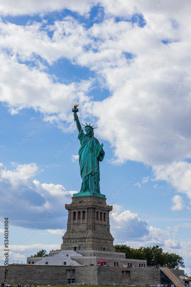 Fototapeta premium Close-up view of Statue of Liberty on Liberty Island in New York against blue sky with white clouds.