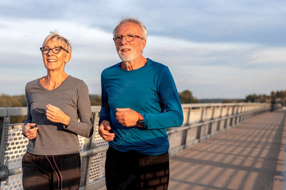 Mature couple man and woman jogging outside and smile