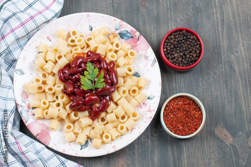 Delicious macaroni with beans and pepper on a wooden table