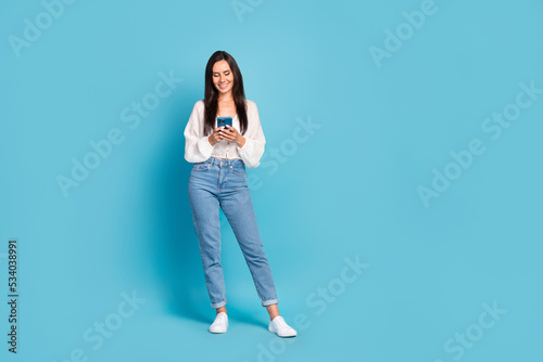 Full size portrait of charming positive girl hold use telephone empty space isolated on blue color background