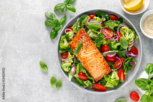 Photo Grilled salmon fish fillet and fresh green leafy vegetable salad with tomatoes, red onion and broccoli
