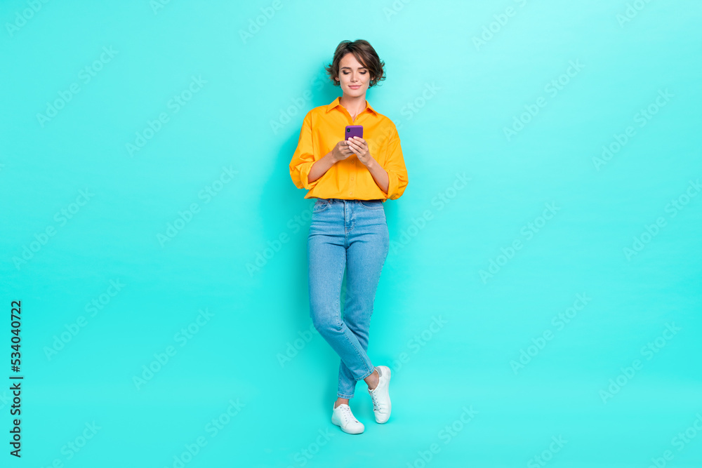 Full length photo of blogger addicted user hand hold telephone device write post scroll read news isolated on cyan color background Full length photo of blogger addicted user hand hold telephone device write post scroll read news isolated on cyan color background